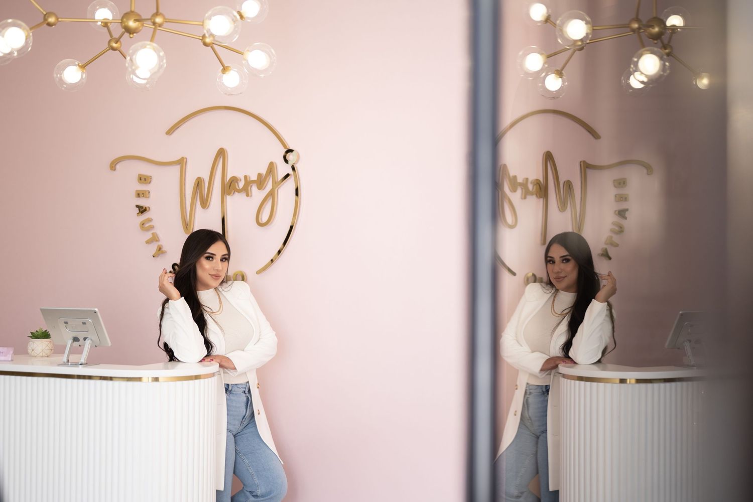Modern beauty salon interior with gold logo and mirrored reception area.