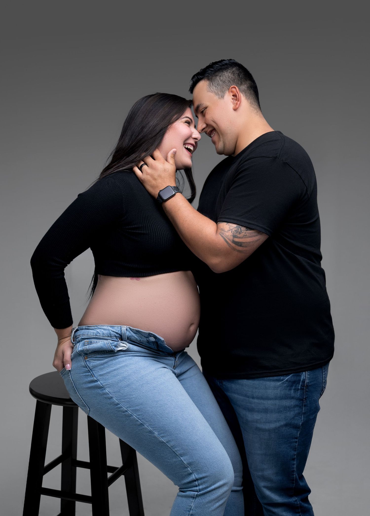 A couple in black and denim performs a playful dance sequence against a gray backdrop.