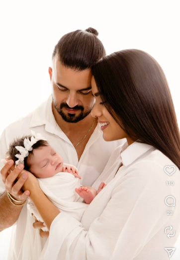Parents in white outfits sharing tender moments with their newborn in studio setting.