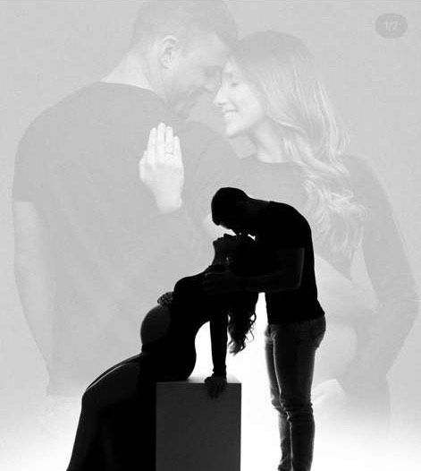Artistic black and white maternity photo with couple silhouette and soft focus background.