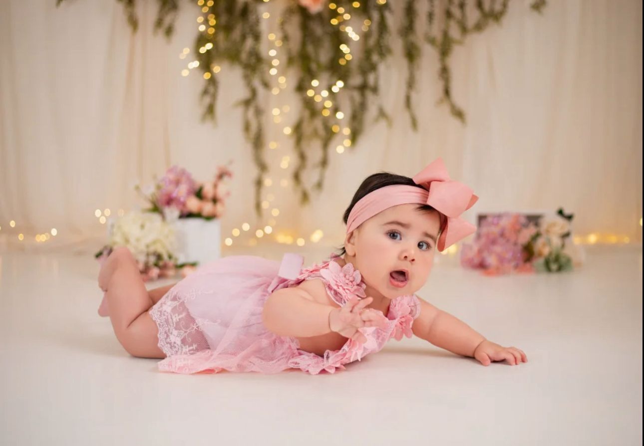 Dreamy baby photography with golden twinkle lights and pink tulle decorations.