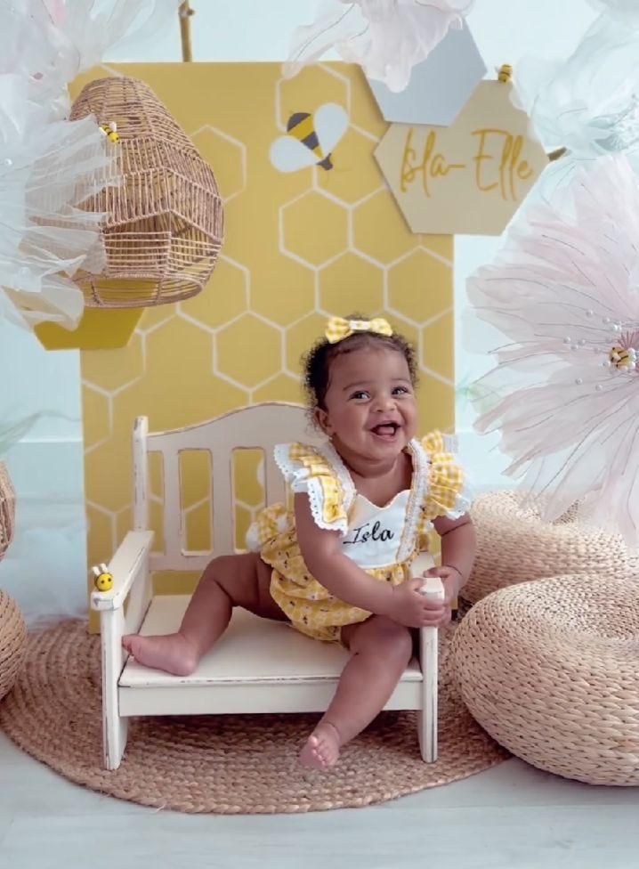 A series of photos showing a baby in yellow outfit sitting on a round woven mat with honeycomb decorations in the background.