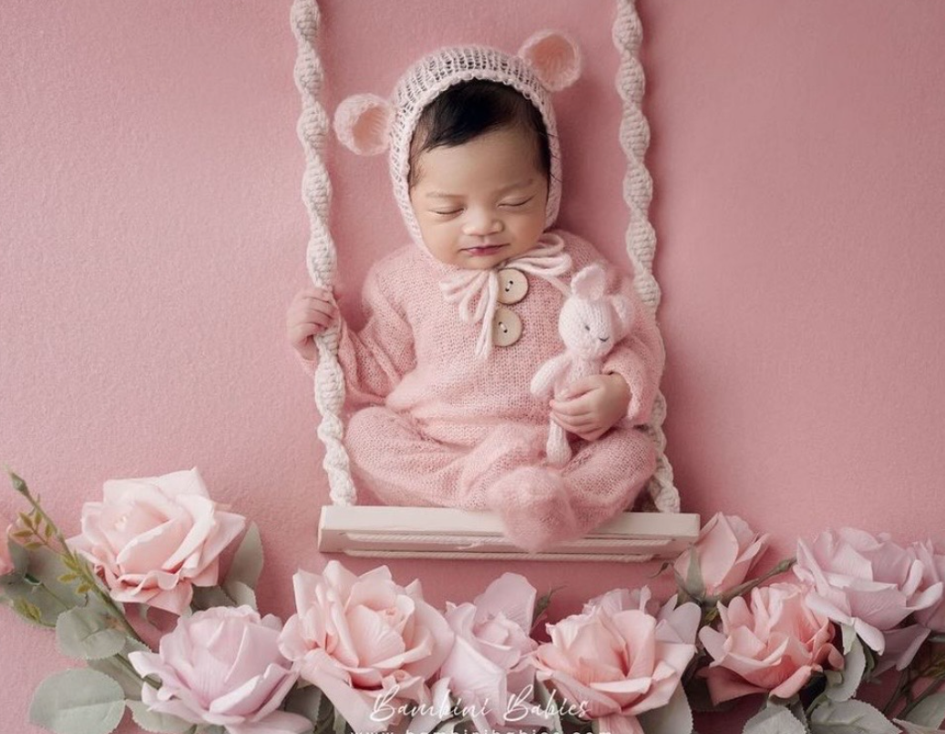 A collage of five baby portraits with pink roses and delicate decorations against a soft pink background.