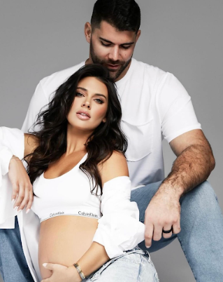 A couple in white clothing pose together in an intimate fashion photography style portrait.
