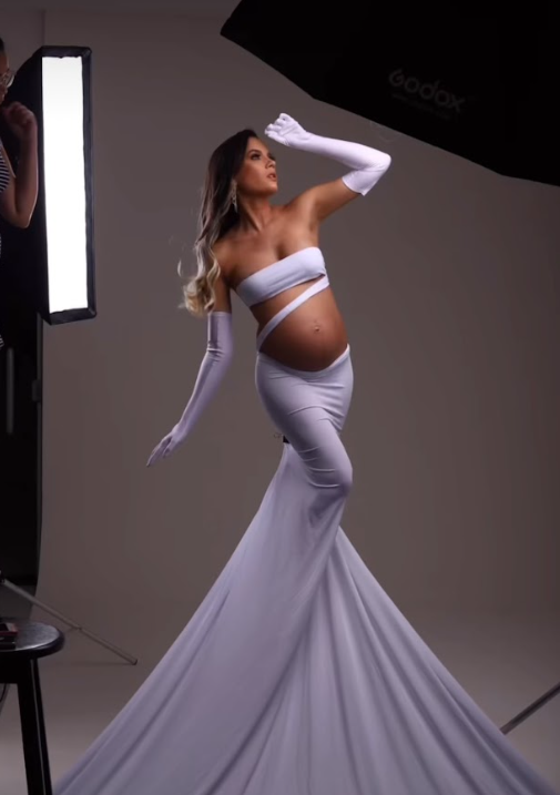 Graceful maternity dance poses in flowing lavender gown against studio backdrop.