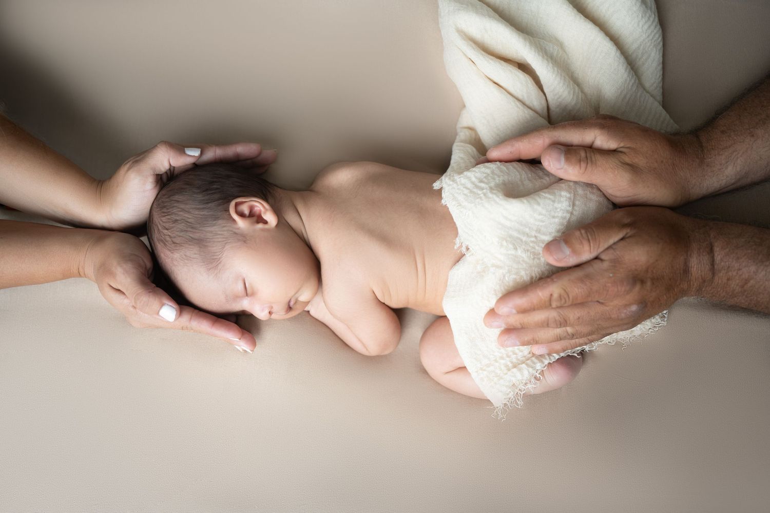 Newborn baby being gently wrapped in a soft white towel during a tender care moment.