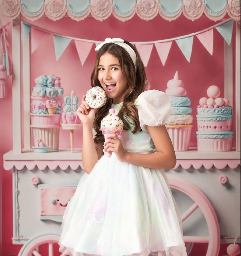 Pink and white themed party backdrop with decorative cupcakes and bunting banners.