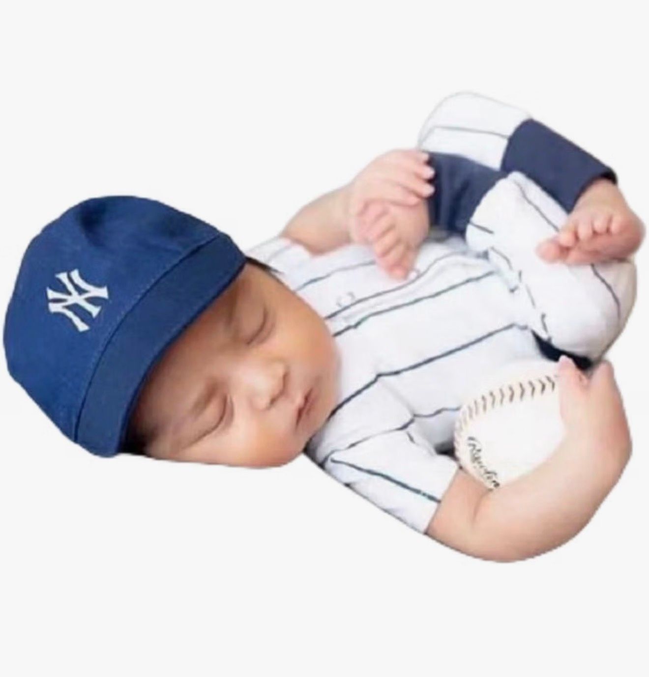 Sleeping newborn baby wearing a New York Yankees baseball cap and pinstripe onesie, holding a baseball.