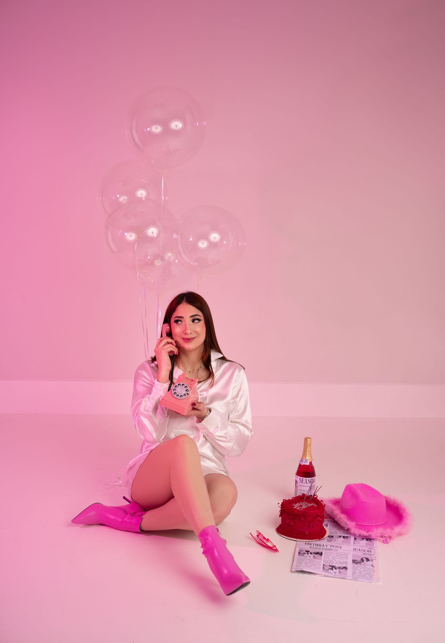 Valentine themed photo with pink backdrop, clear balloons and festive party accessories.