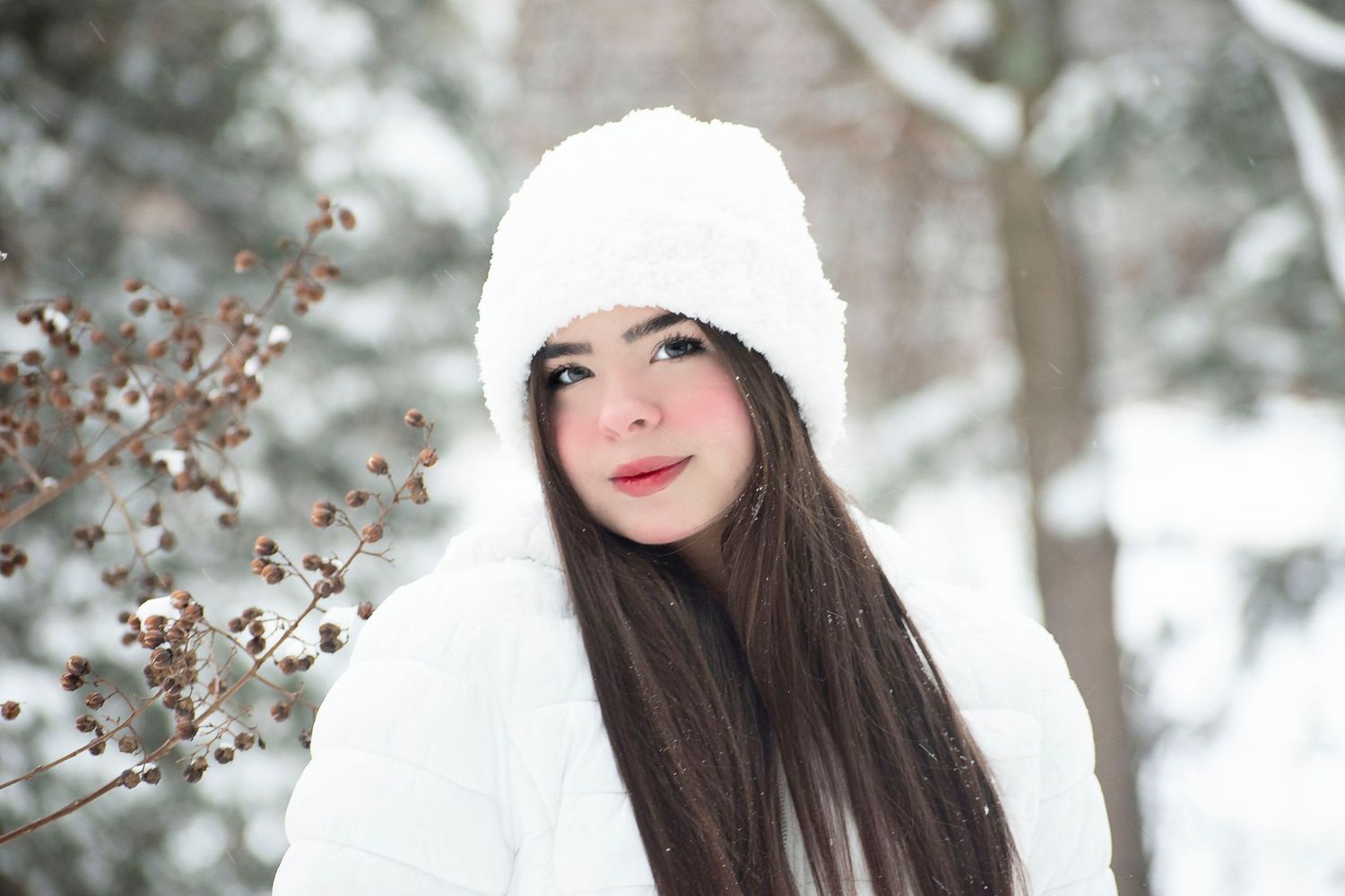 Winter portrait with white knit hat and coat in snowy nature setting.