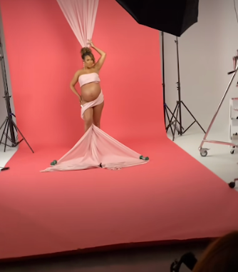 Professional photography studio setup with pink backdrop and lighting equipment visible.