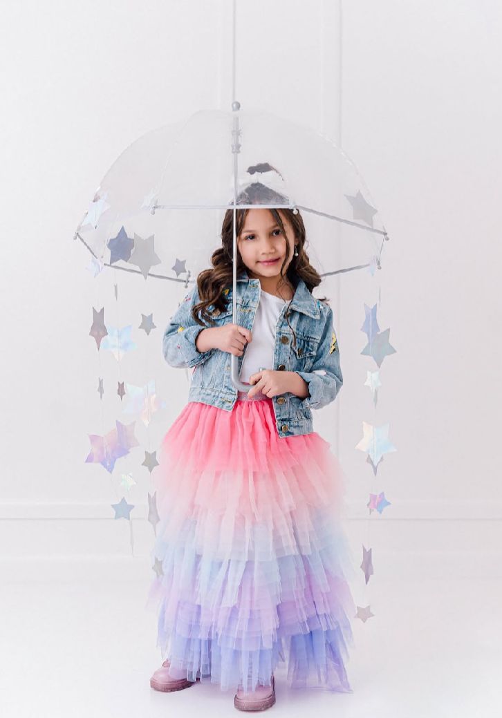 Magical star-themed setup with holographic decorations and pastel tulle dress against white background.