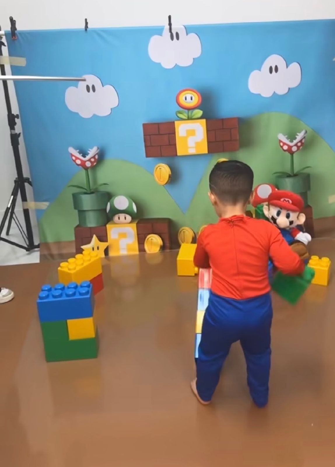 Colorful Super Mario themed play area with clouds, blocks and scenery against a wall.
