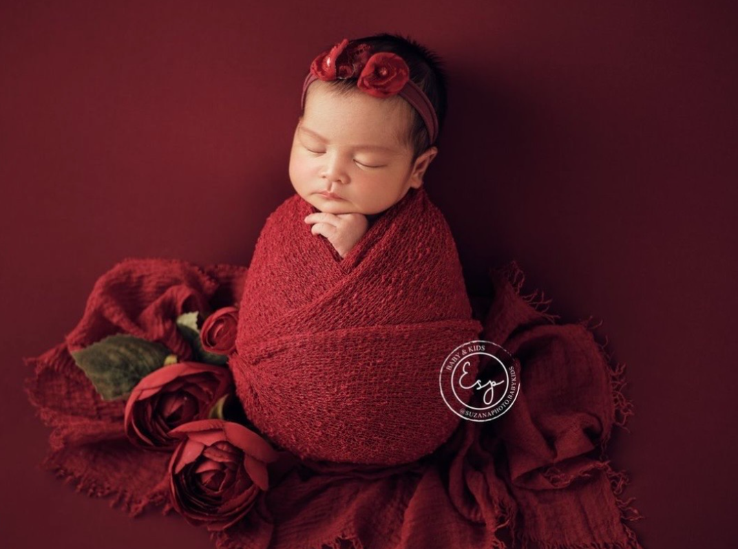 Newborn photography collage featuring burgundy red tones with sleeping baby posed in soft wraps and floral accents.