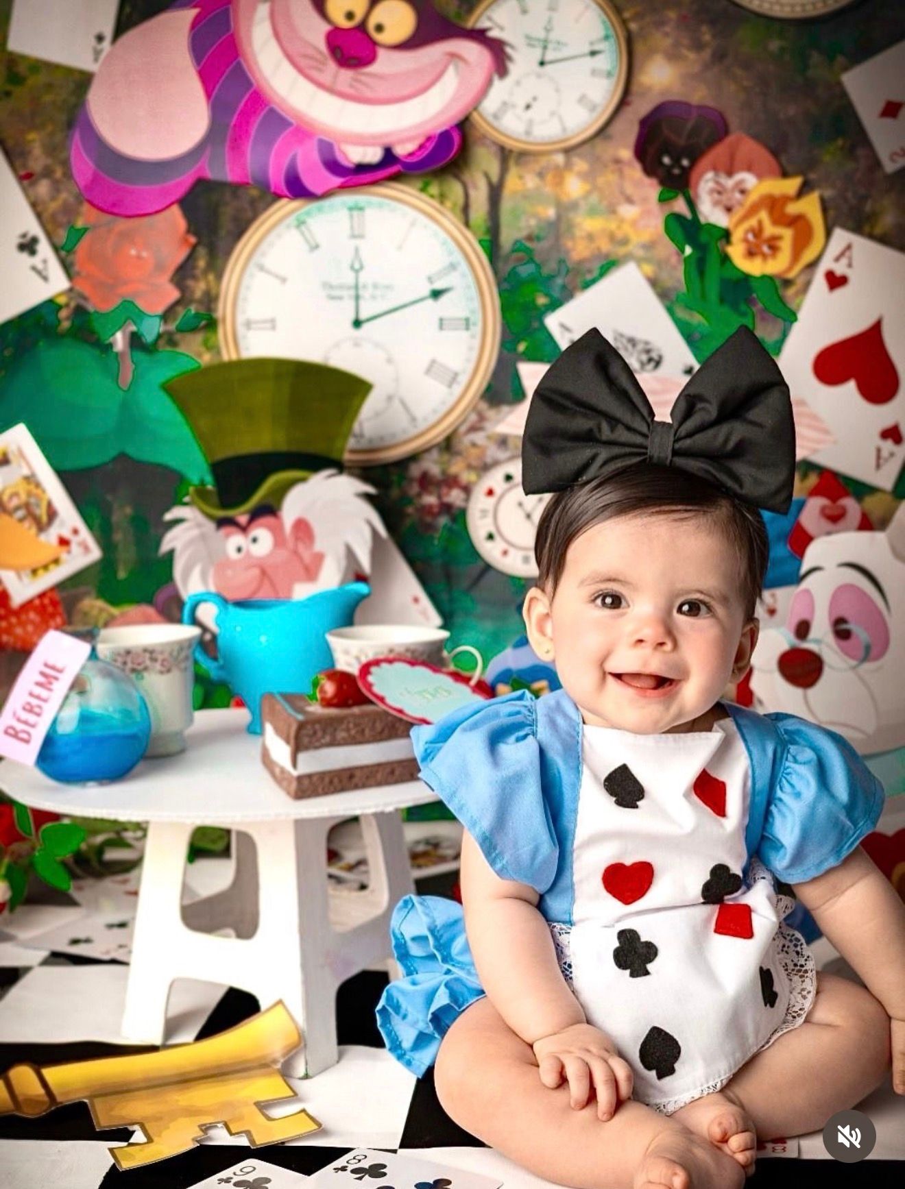Baby girl in Alice in Wonderland costume smiles at Alice in Wonderland themed birthday photoshoot.