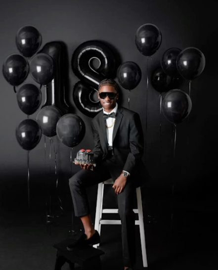 Elegant celebration scene with black balloons and number 18 decor against dark background.