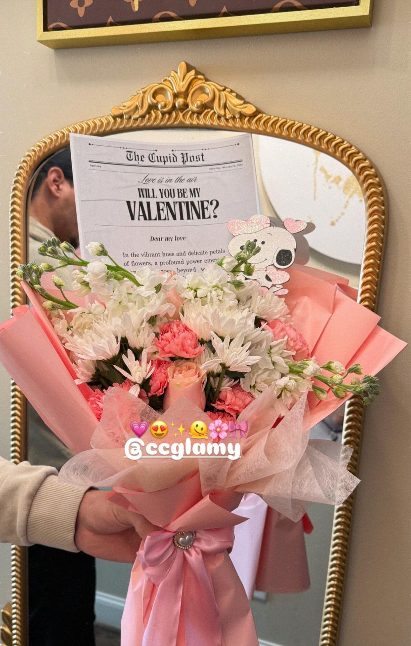 Pink Valentine's Day bouquet with white flowers and a Cupid Post card in a gold mirror frame.