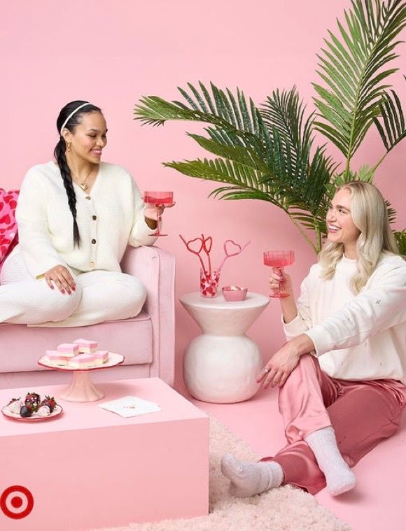 Two women in pink and white outfits toast with pink drinks in a Valentine's Day Target lifestyle setting.