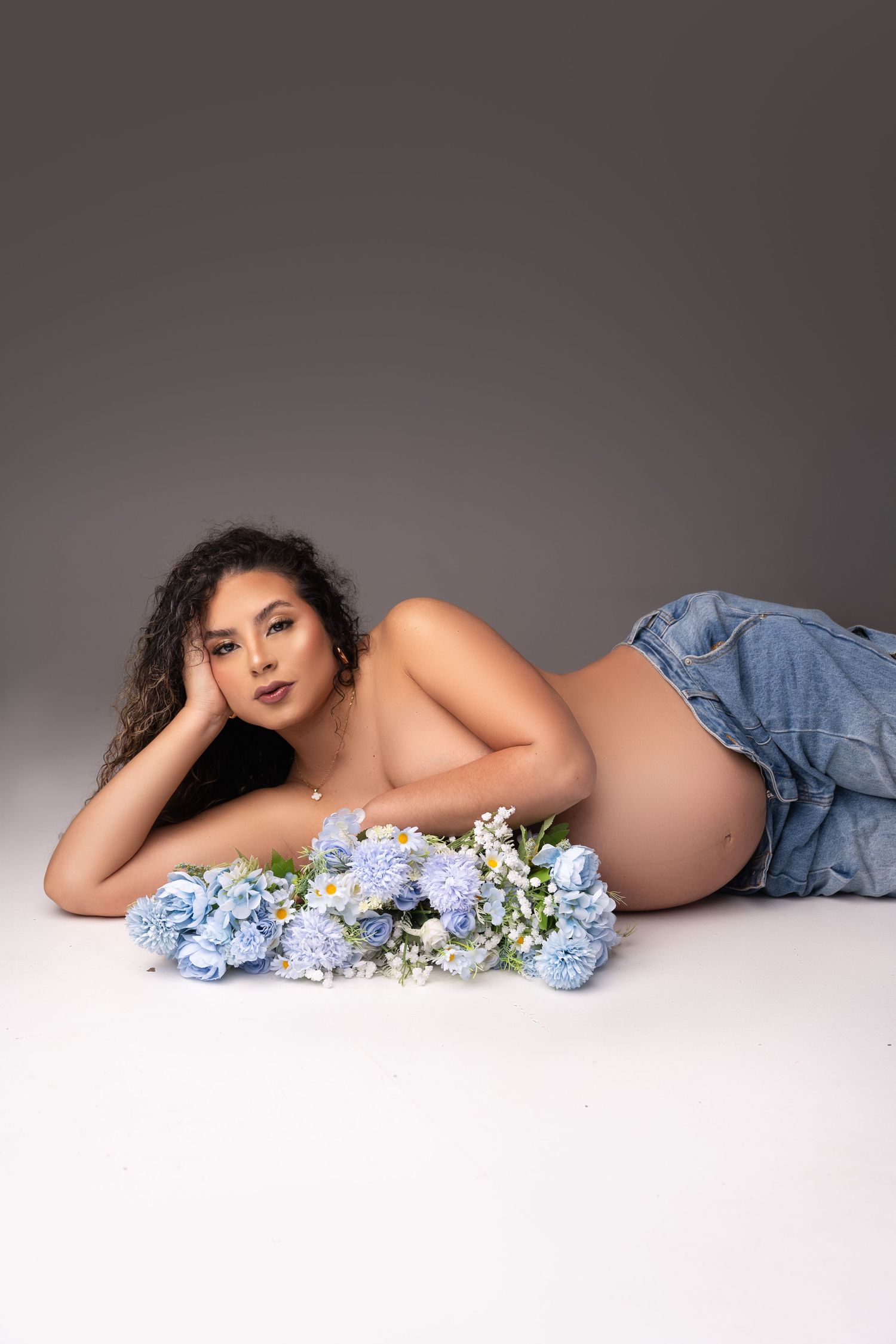 A boudoir photoshoot featuring soft blue hydrangeas and denim against a white backdrop.