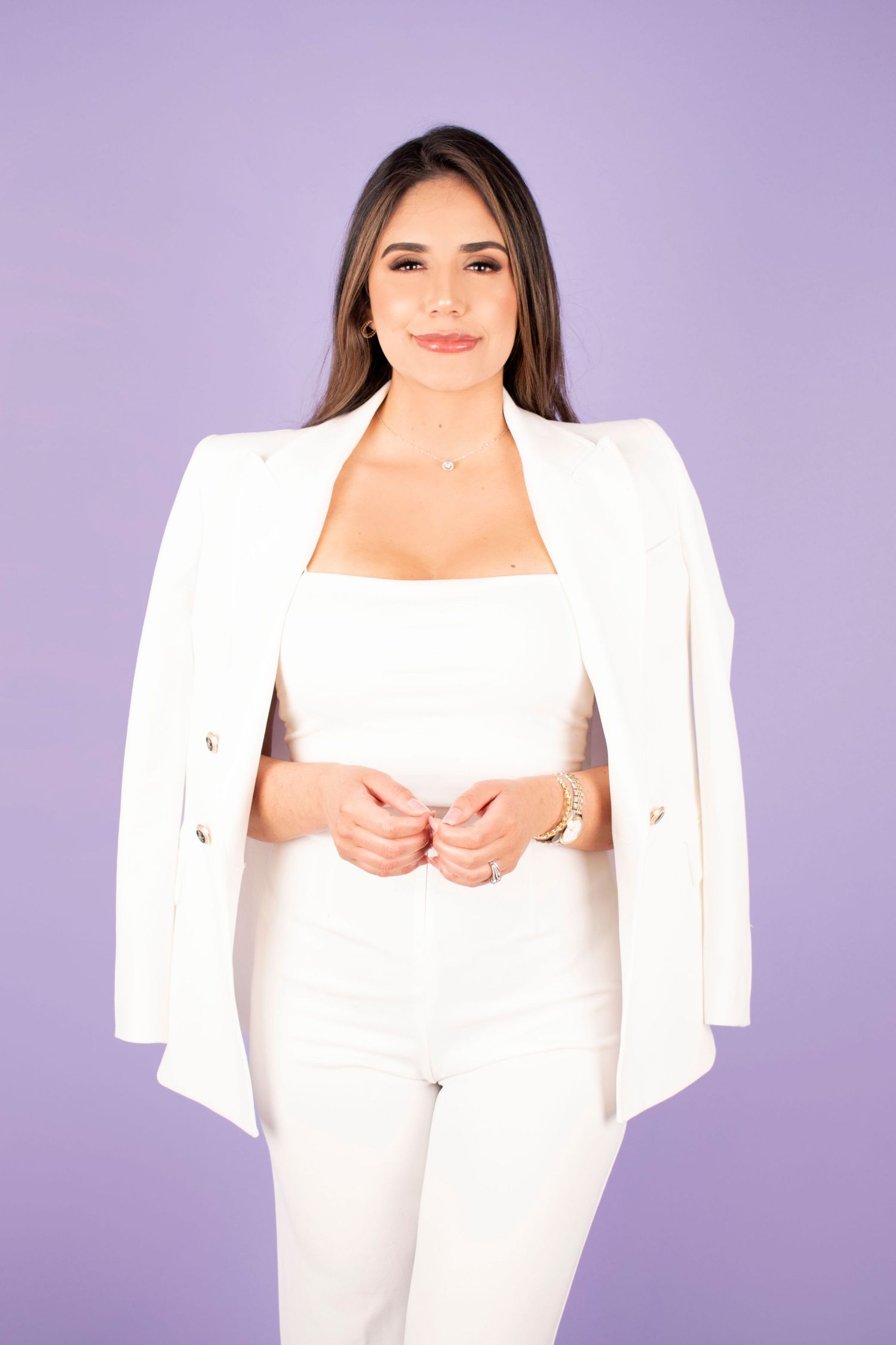 Professional wearing an elegant white pantsuit and blazer poses confidently against a purple background.