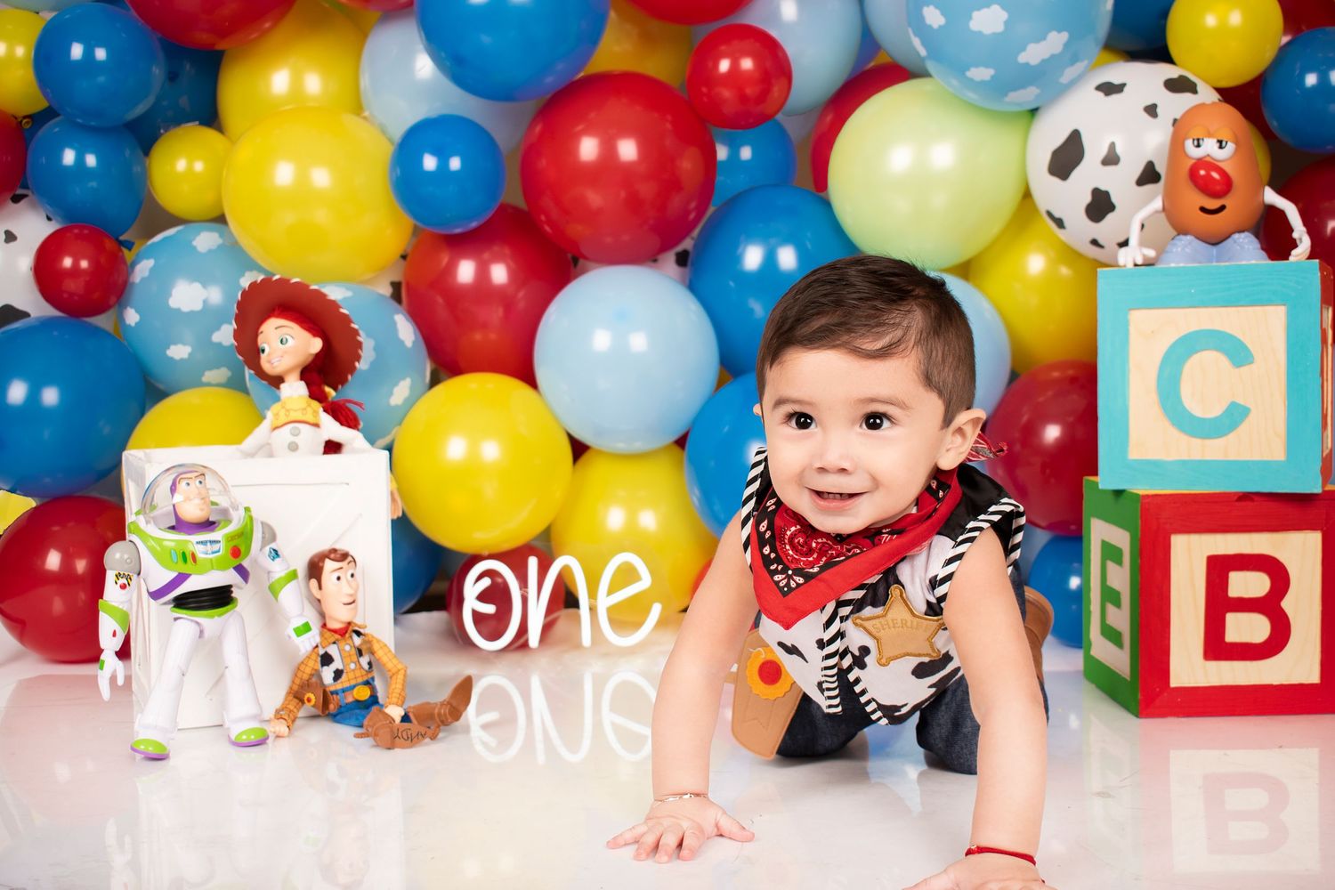 Colorful balloon backdrop with toys and alphabet blocks for first birthday.