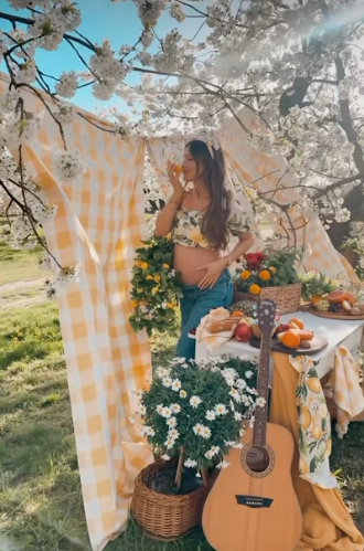 A spring picnic scene with an acoustic guitar, wicker basket, and blooming cherry blossoms against a checkered blanket.