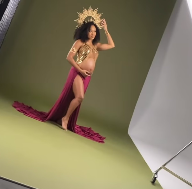 Model poses gracefully in a studio setting with magenta fabric, showcasing artistic movement and form.
