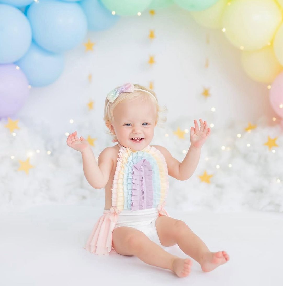 Whimsical baby photography setup with soft pastel balloons and dreamy lighting creating magical atmosphere.