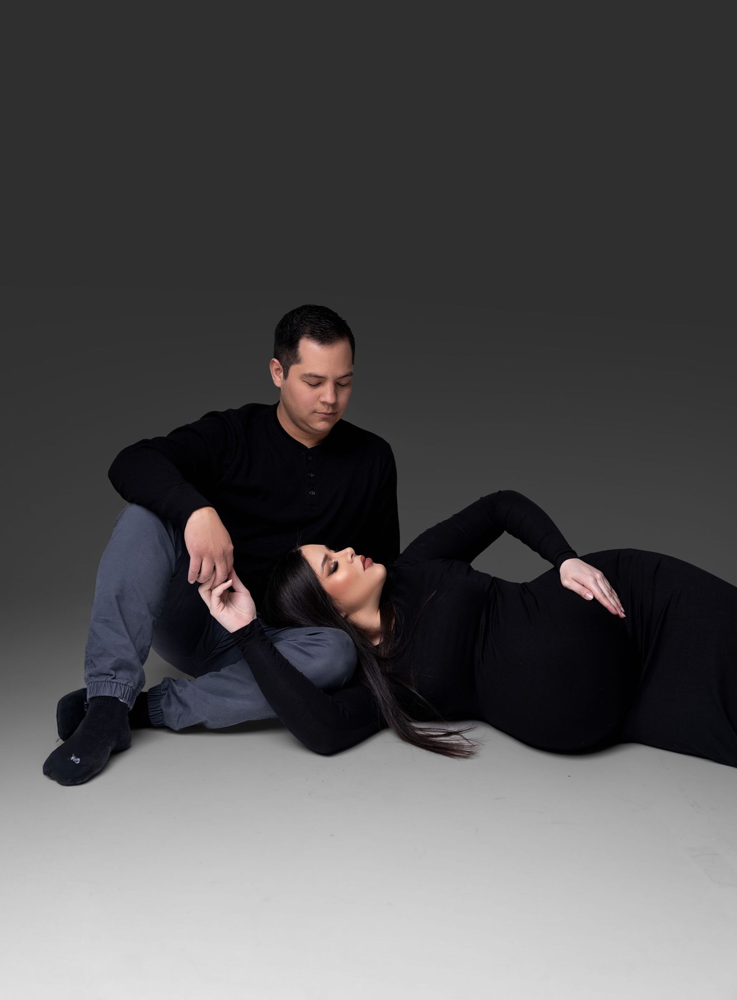 A series of four dramatic black and white photos showing two people in dark clothing lying on a light surface.