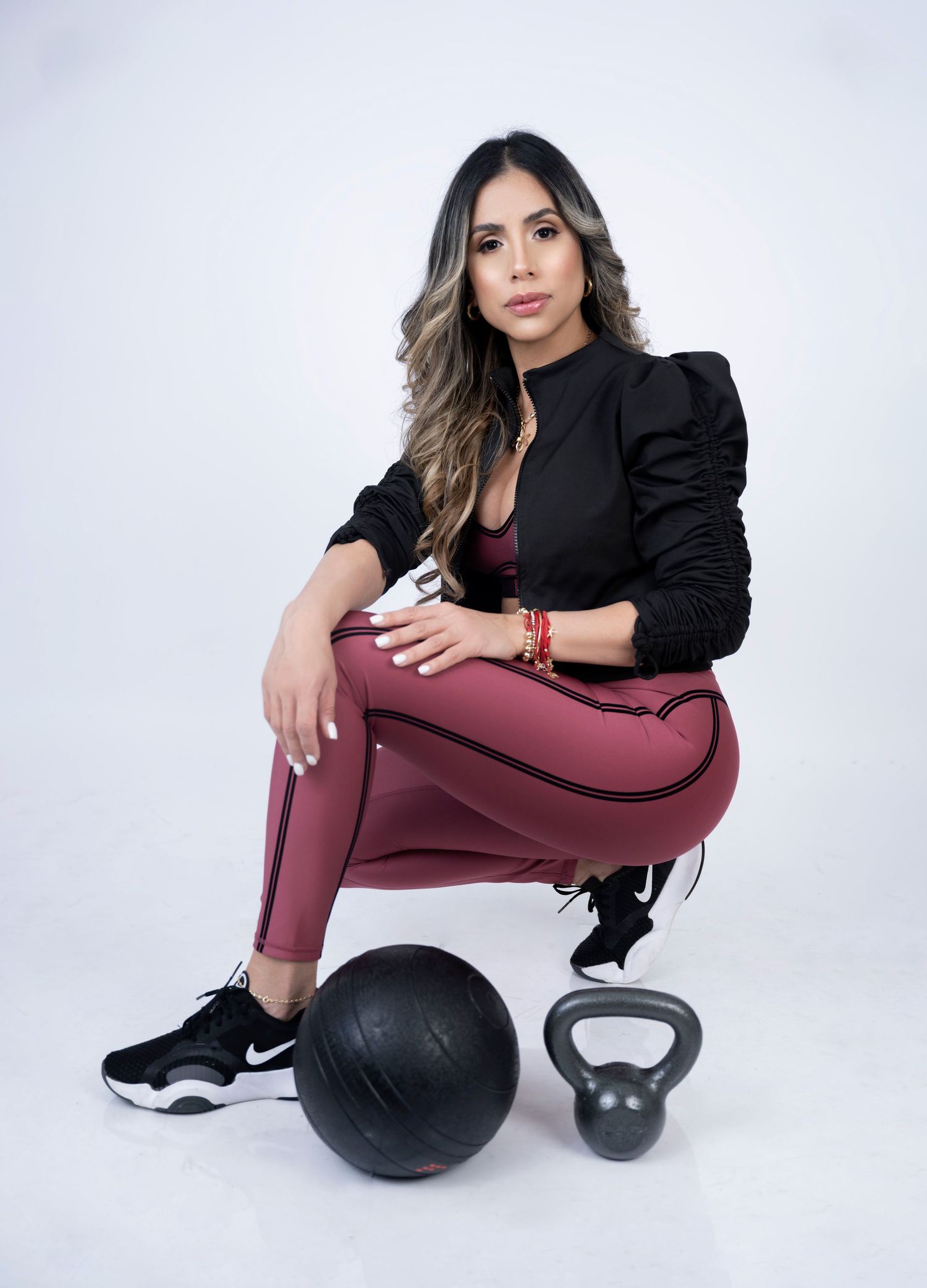 Fitness portrait with person in black jacket posing with exercise equipment.