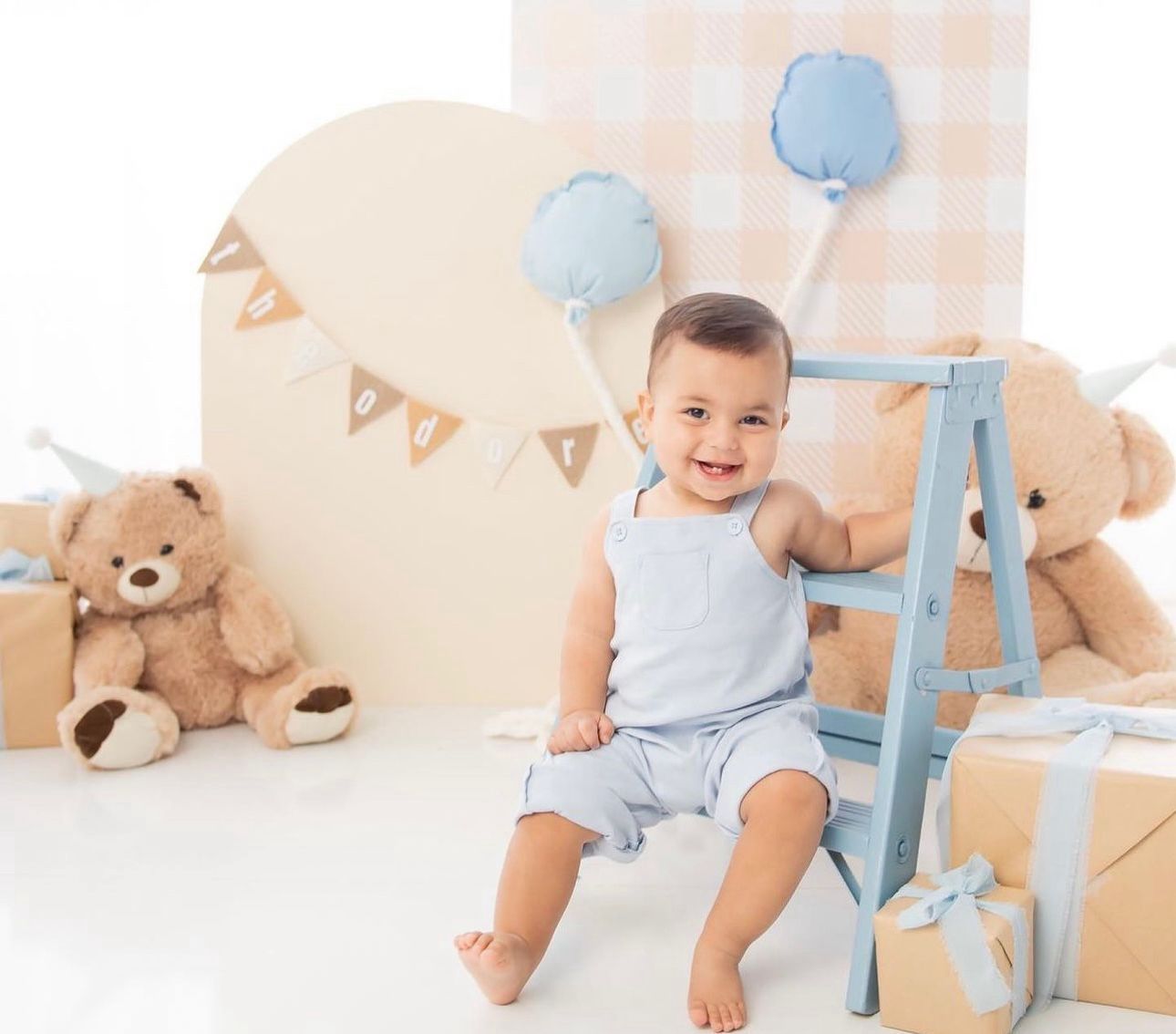 Baby celebration setup with blue balloons, teddy bear, and bunting decorations.