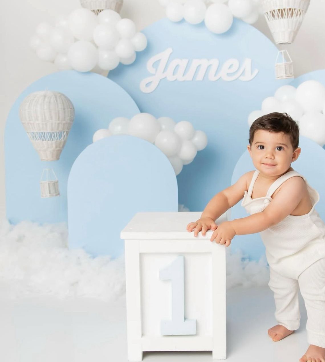 White studio setup with cloud decorations and hot air balloon theme for baby photography.