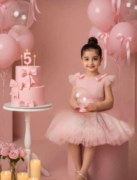 A young girl in a pink tutu dress poses beside a 5th birthday cake surrounded by pink balloons and decorations.