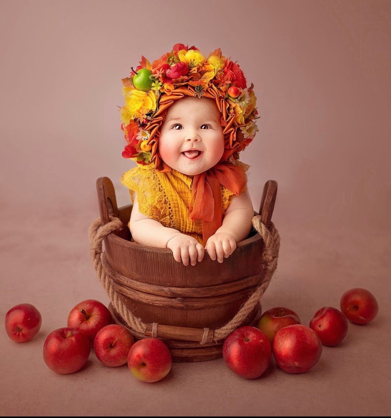 Autumn themed portrait with fall leaves crown and red apples surrounding a wooden barrel prop.