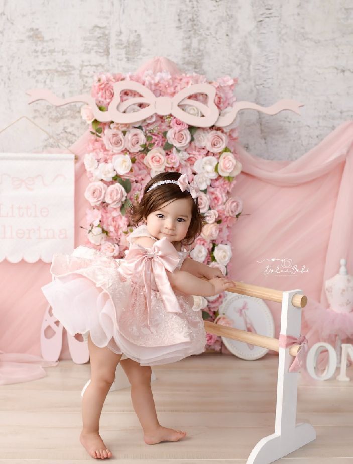 Romantic pink floral backdrop with white furniture and delicate rose arrangements in a dreamy photography setup.