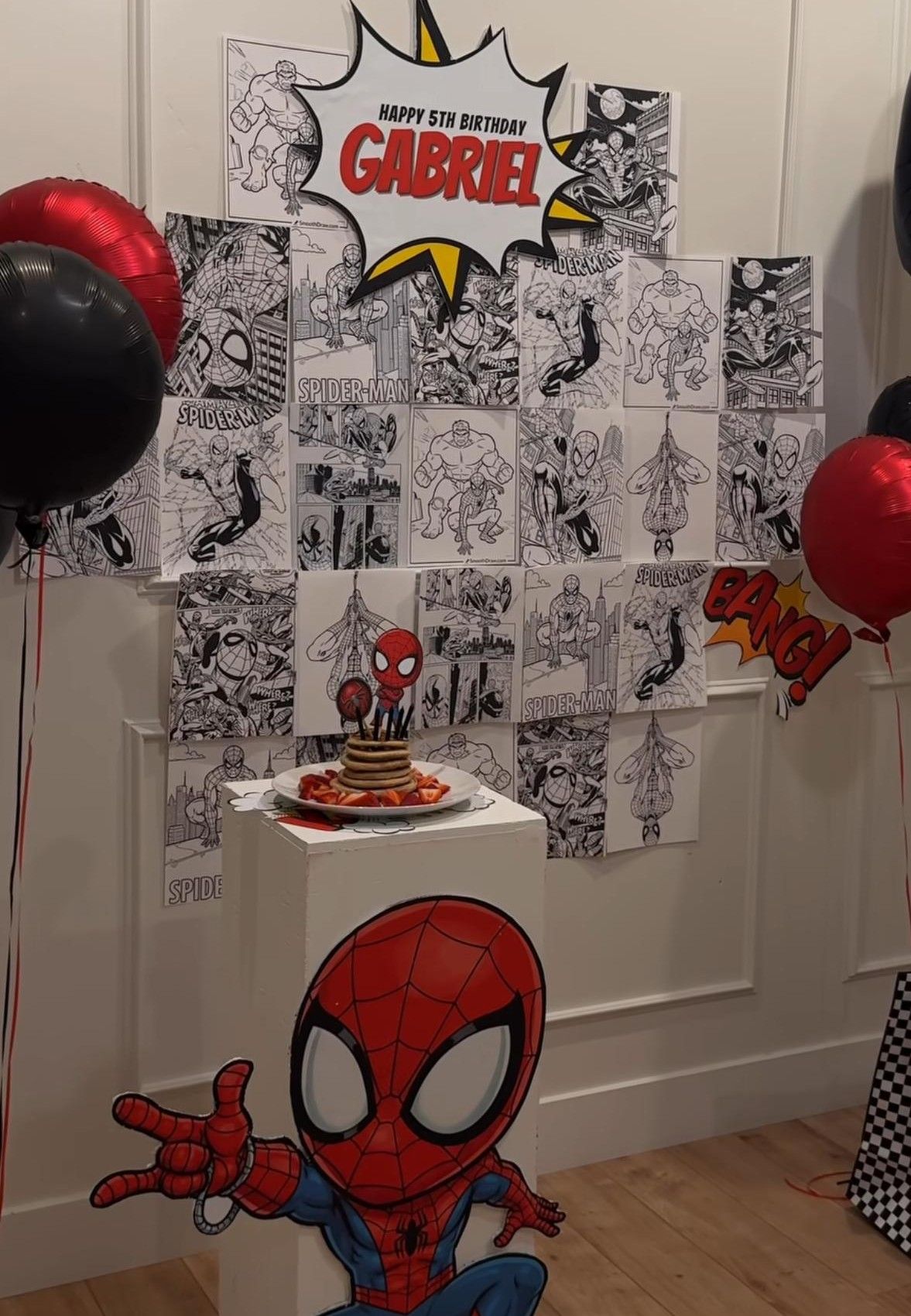 Spider-Man themed 5th birthday party setup for Gabriel with comic strip backdrop, red and black balloons, and cake display.