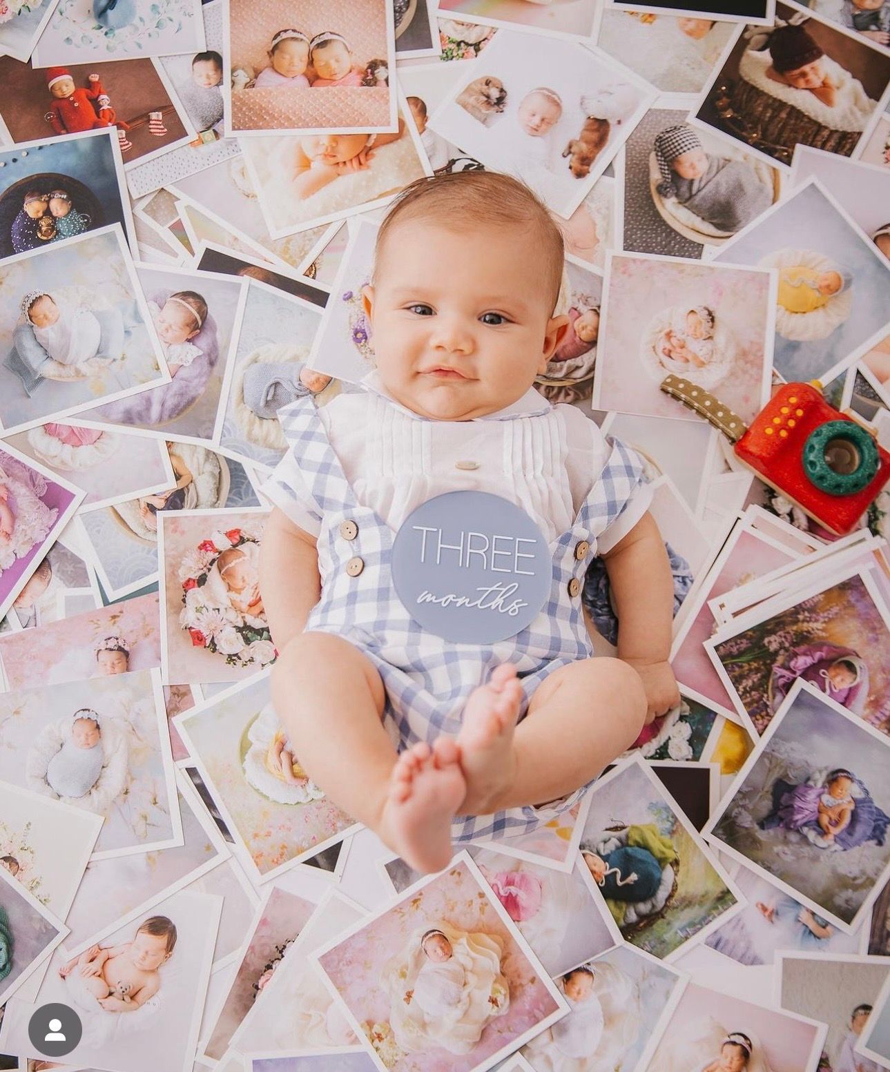 Three month old baby lying on scattered polaroid photos wearing white bodysuit.