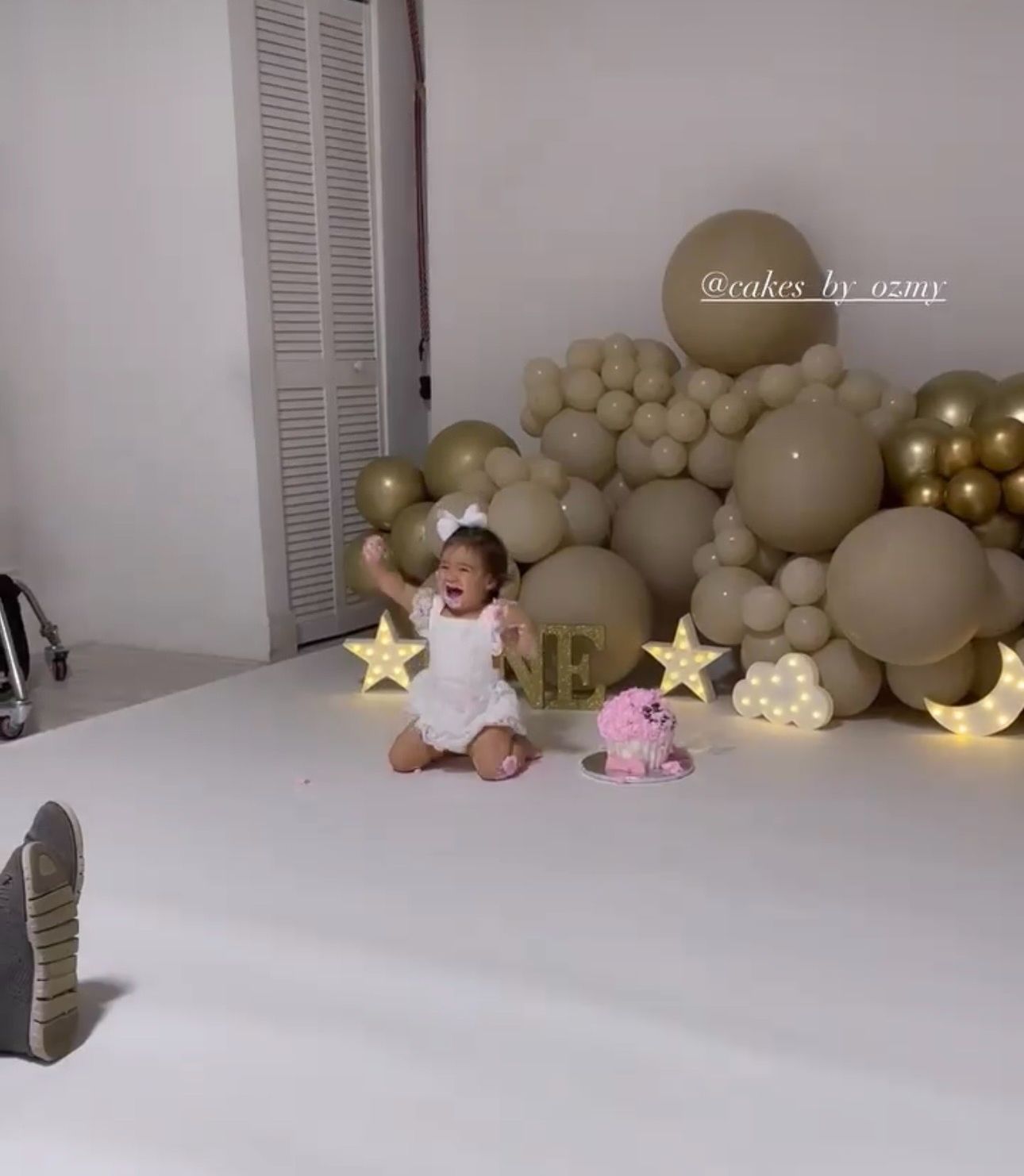 Soft beige balloon arch with plush toys and moon decorations for a nursery-themed setup.