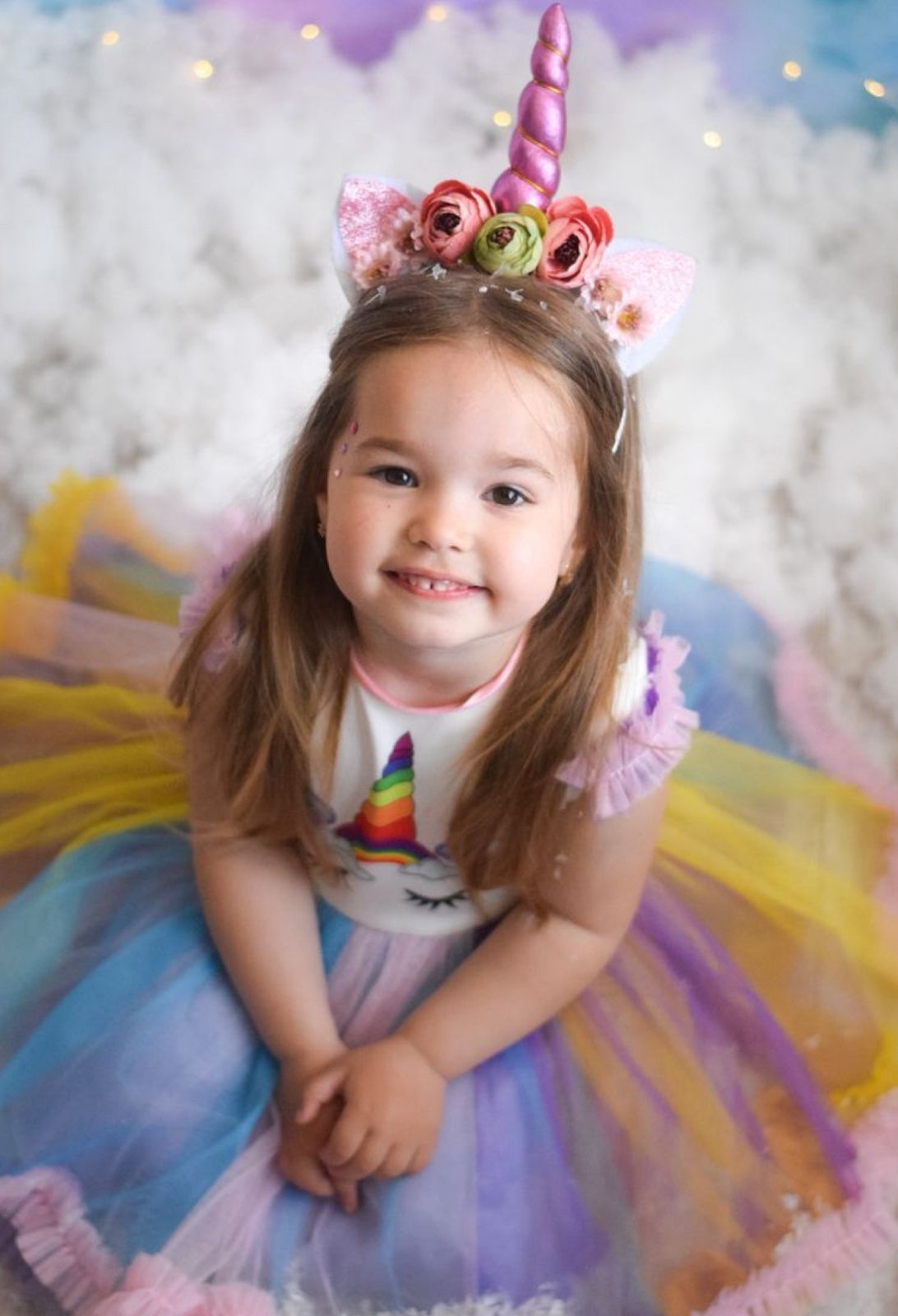 A magical unicorn-themed portrait with a sparkly headpiece, tulle dress, and dreamy pastel background.