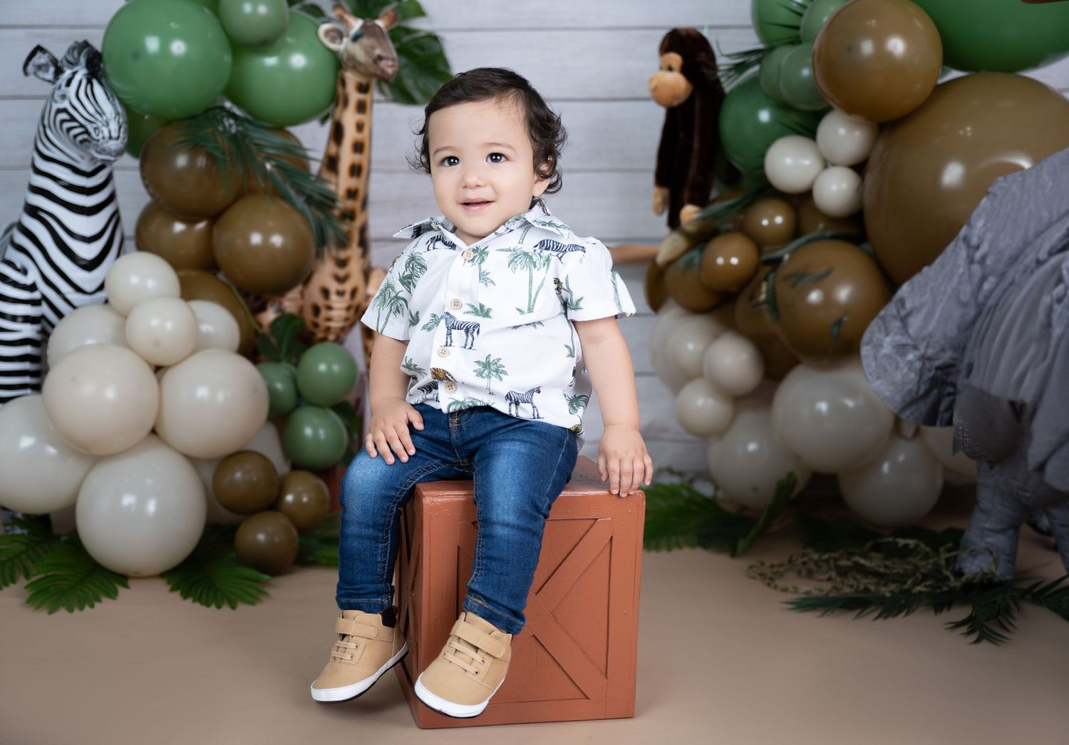 Safari themed photoshoot with patterned shirt and decorative balloon arch.