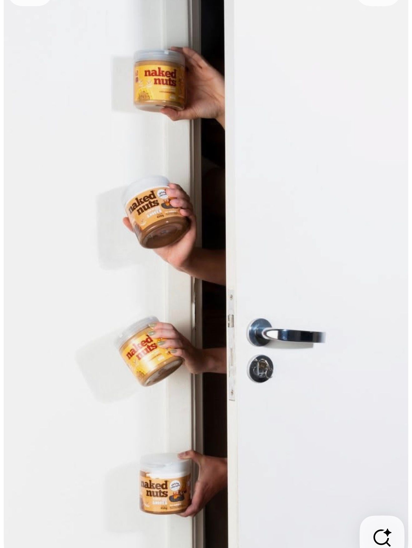 Four jars of Naked Nuts peanut butter held through a white door, showcasing the product range.