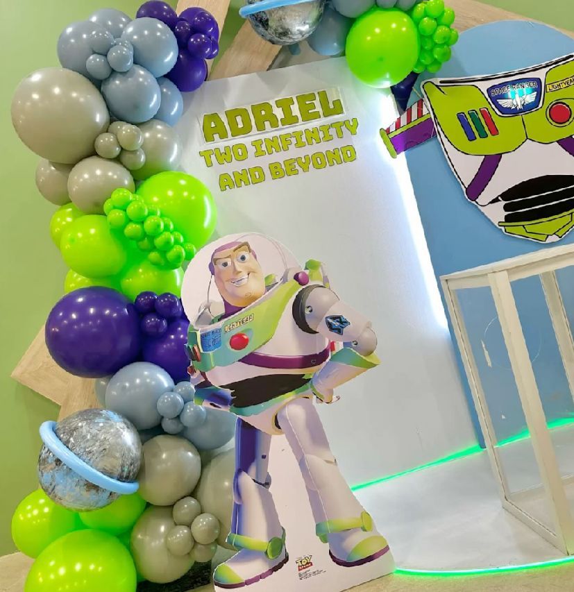 Buzz Lightyear themed party display with purple, green and silver balloon arrangements and decorative elements.