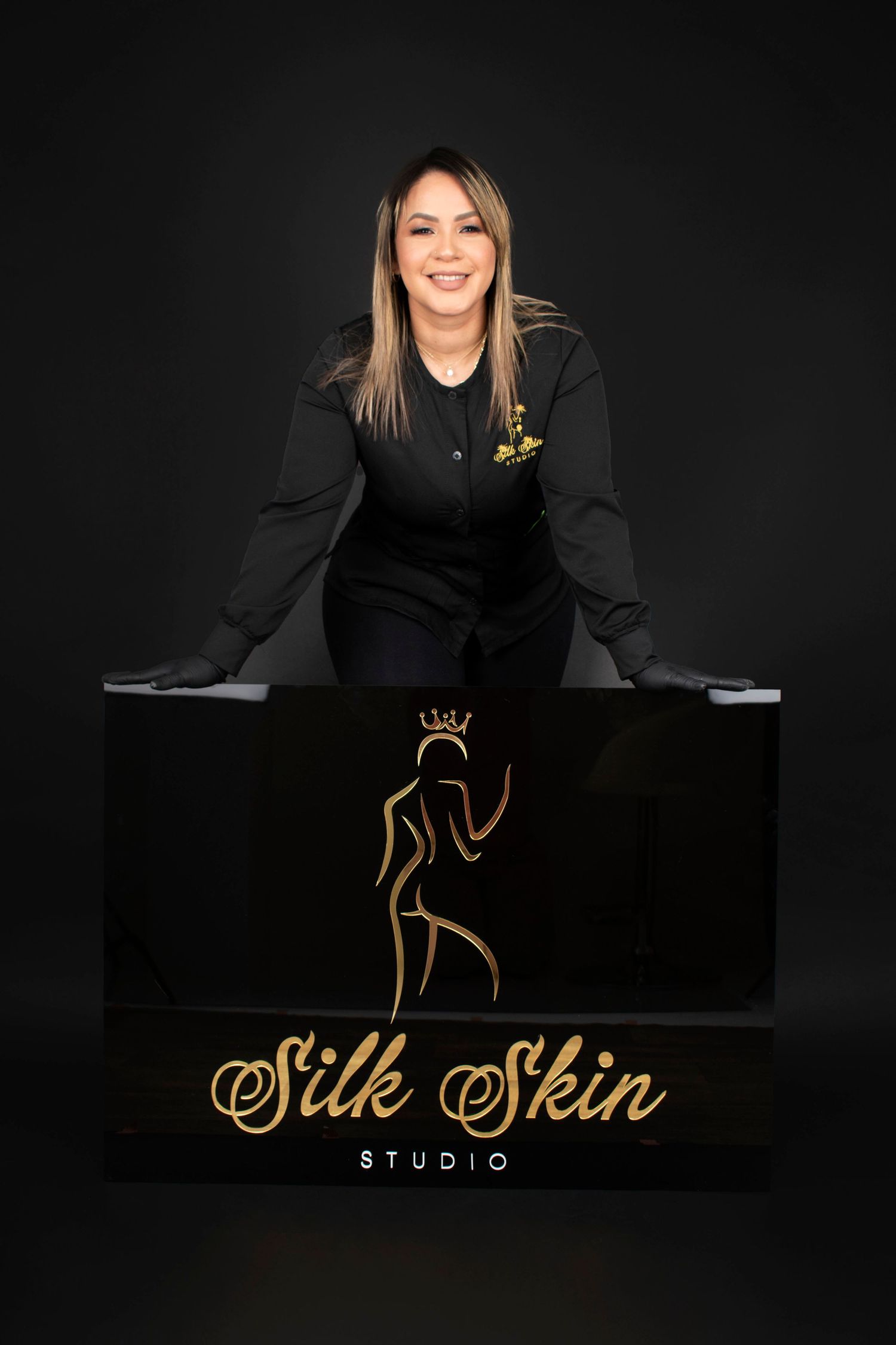 Business professional poses with Silk Skin Studio branded display against dark background.
