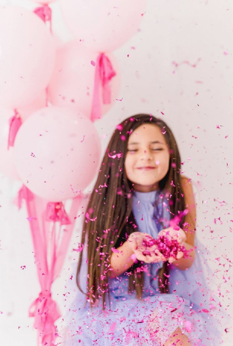 A joyful moment captured with pink glitter and confetti against a light background.