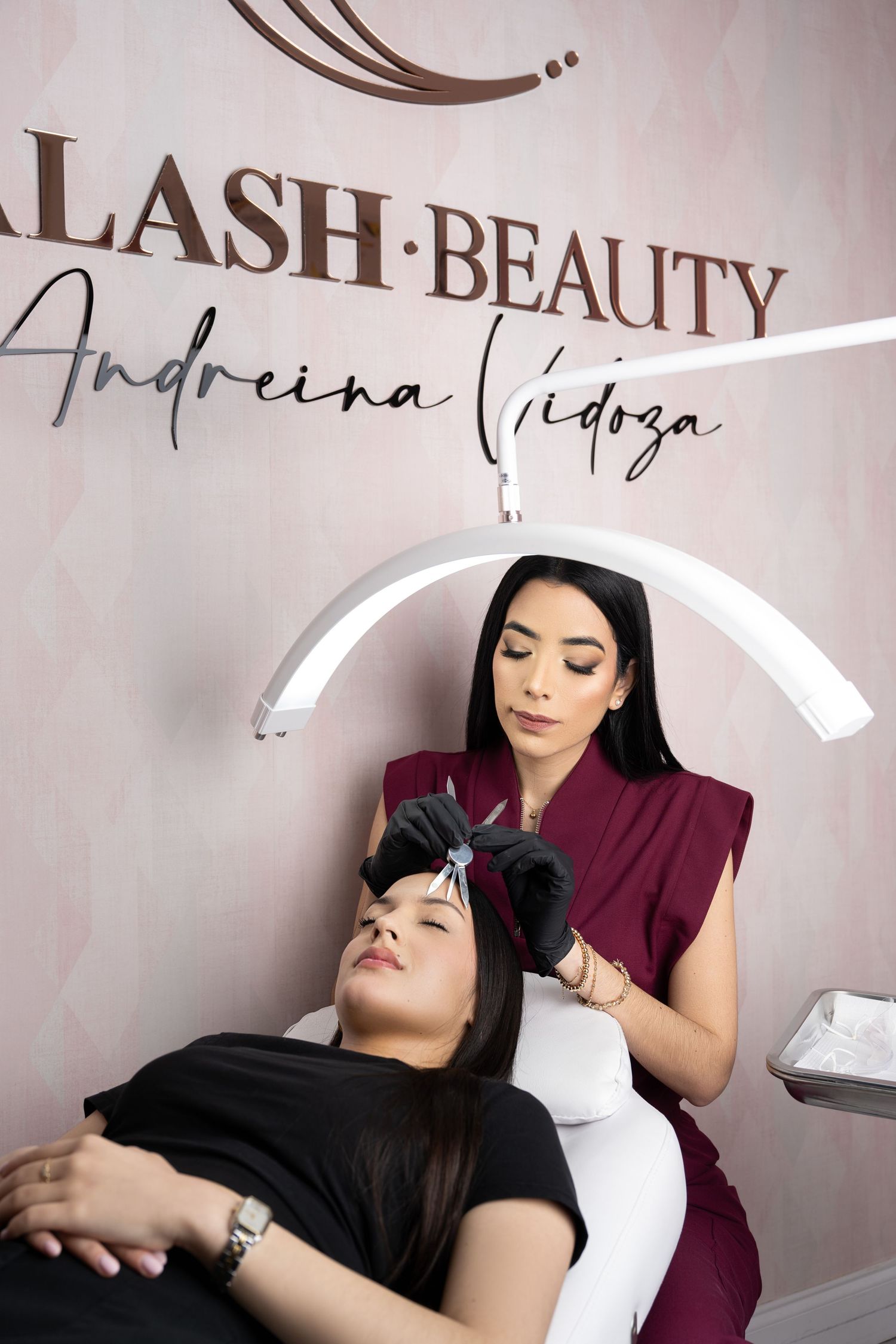 Esthetician applying lash extensions to client at Alash Beauty salon by Andreina Vidoza.