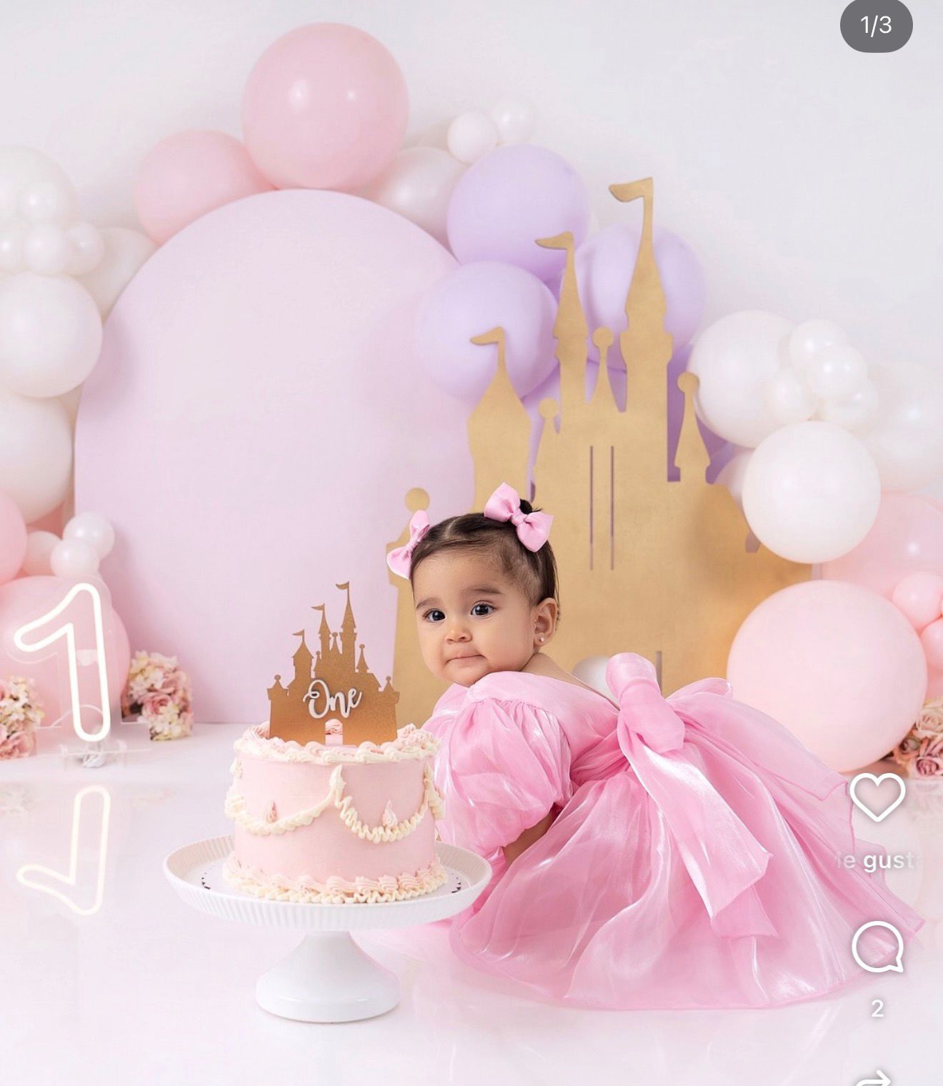 Baby girl in pink tutu dress at princess-themed first birthday cake smash photo session.