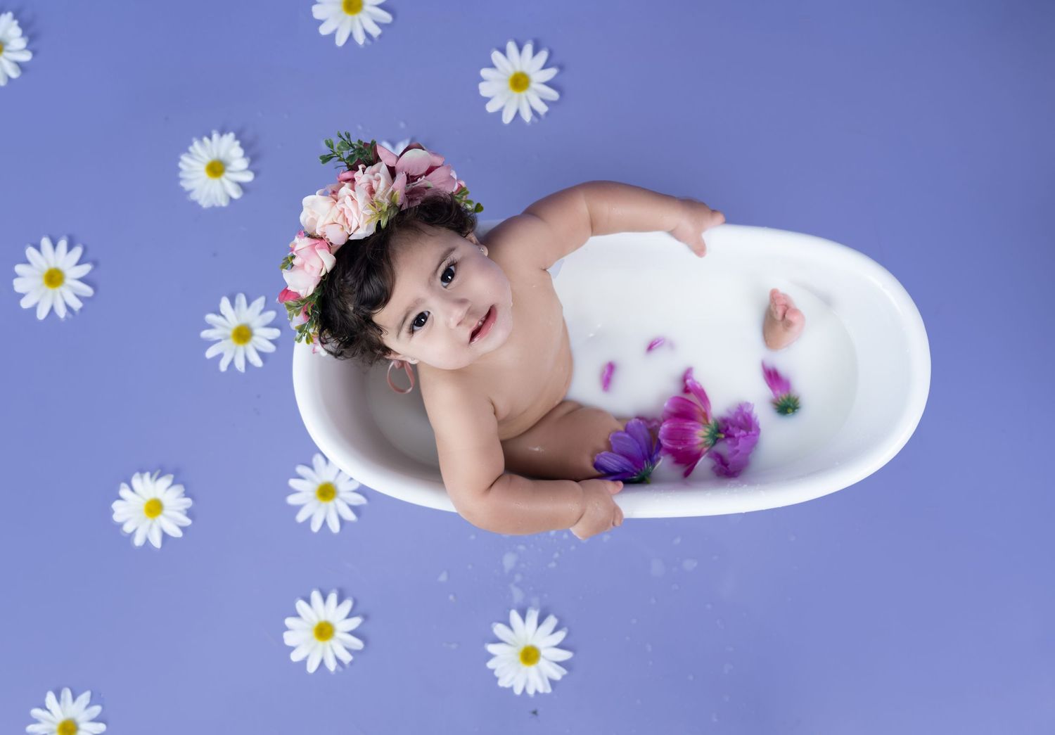 Baby milk bath photo with flower crown and daisies on purple background.