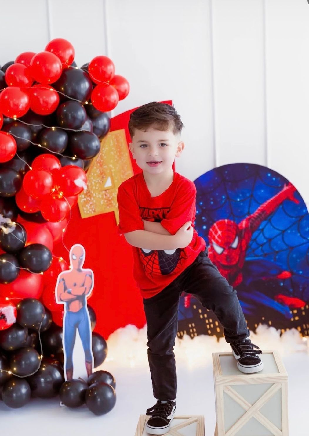 A Spider-Man themed birthday party setup with red and black balloon decorations against a blue backdrop.