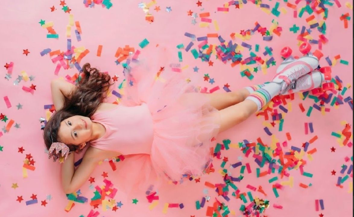 Colorful confetti falling on pink background creating a festive celebration scene.