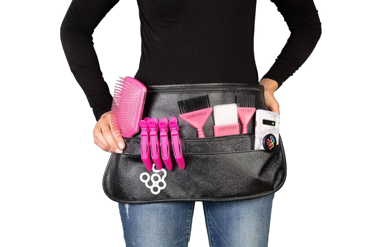 Black leather hairdresser waist tool belt with pink hair brushes, clips, and styling accessories.